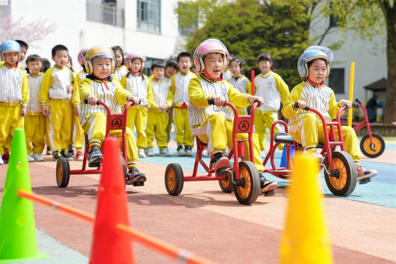 中國廣東、江蘇、浙江等6省向來被視為人口大省，去年出生數都不增反減。圖為3月27日浙江省一間幼兒園孩童騎三輪車。（中新社）