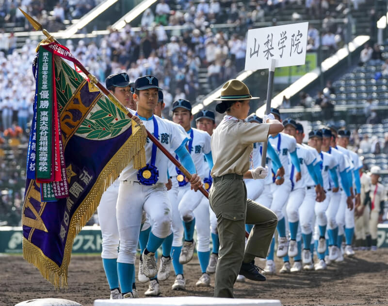 山梨學院總教練吉田洸二率領學生在甲子園奪冠，締造自己第2度率隊在甲子園奪冠紀錄。圖為山梨學院舉優勝旗繞場。（共同社）