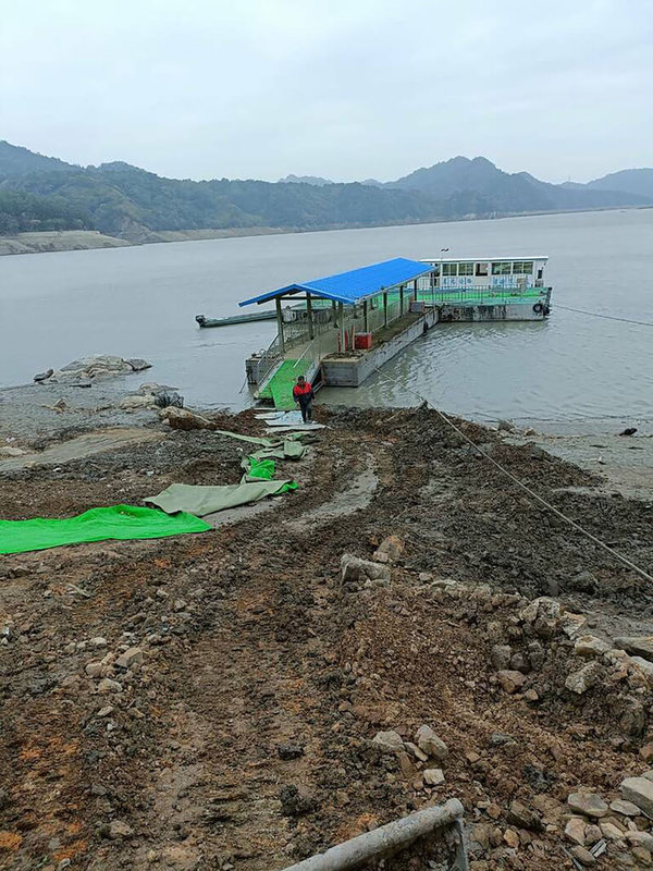 石門水庫蓄水率續降，位於集水區上游的薑母島因水位過低，碼頭已被爛泥包圍，桃園市渡船遊艇商業同業公會近日僱用怪手清除爛泥，挖出護堤道路並加鋪防水地毯，協助島民登船。（陳咪春提供）  中央社記者葉臻傳真  112年4月8日