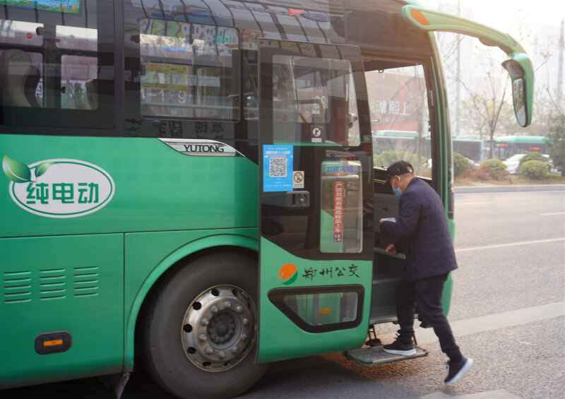 中國12日發布預防COVID-19新指引，民眾搭乘公共交通工具及進入人員密集場所，不再強制要求戴口罩。圖為鄭州市民準備搭乘公車。（中新社）