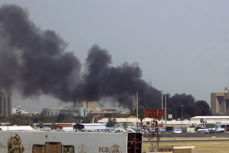 圖為喀土穆國際機場附近建築物15日因快速支援部隊與正規軍交火而冒出濃煙。（法新社）