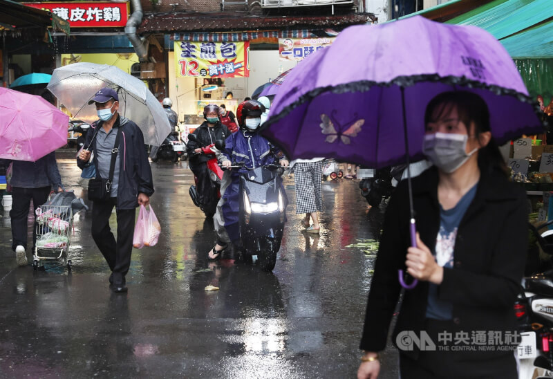 氣象專家吳德榮說，26日雨帶通過，屆時北台灣有局部雨，氣溫略降。圖為民眾撐傘到新北市土城區市場採買。（中央社檔案照片）