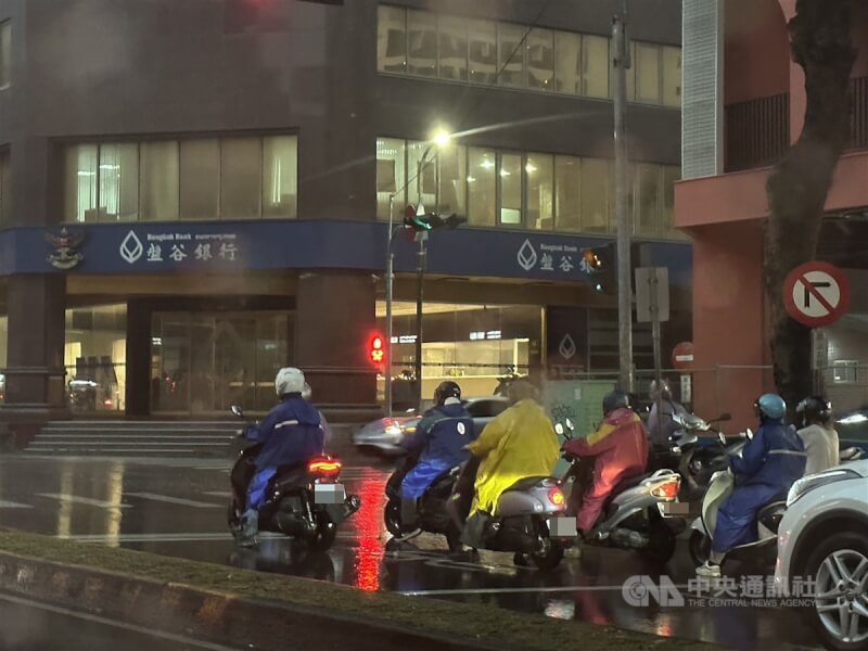 圖為台中機車騎士穿雨衣遮雨。（中央社檔案照片）