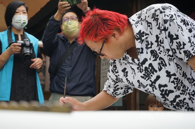 來自日本新潟的街頭書法藝術家曾山尚幸（右）自創Soyamax體，大病痊癒後帶著毛筆環遊世界以筆結緣。中央社記者張祈攝 112年4月22日