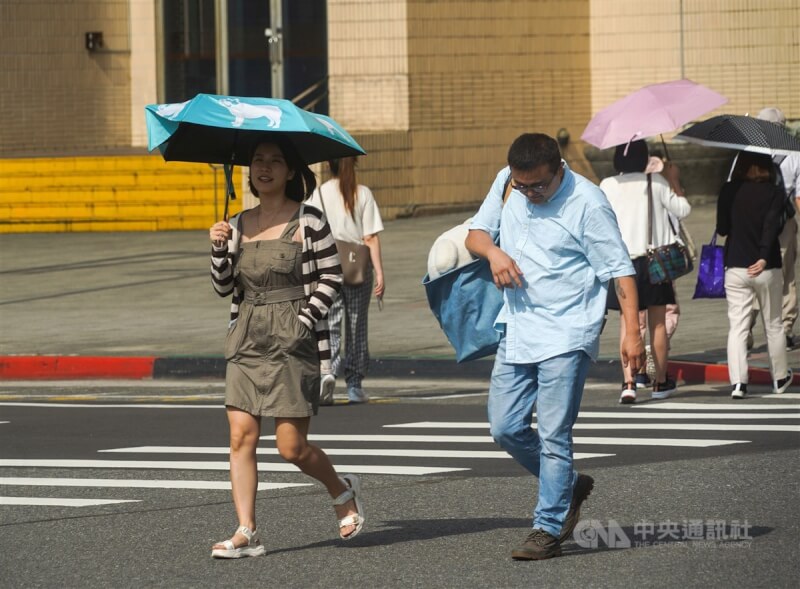 圖為台北地區午後晴朗暖熱，信義區街頭民眾撐起陽傘防曬。（中央社檔案照片）