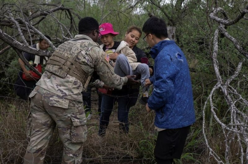 4月5日美國德克薩斯州國民警衛隊協助一對中國母女越過圍欄。（路透社）