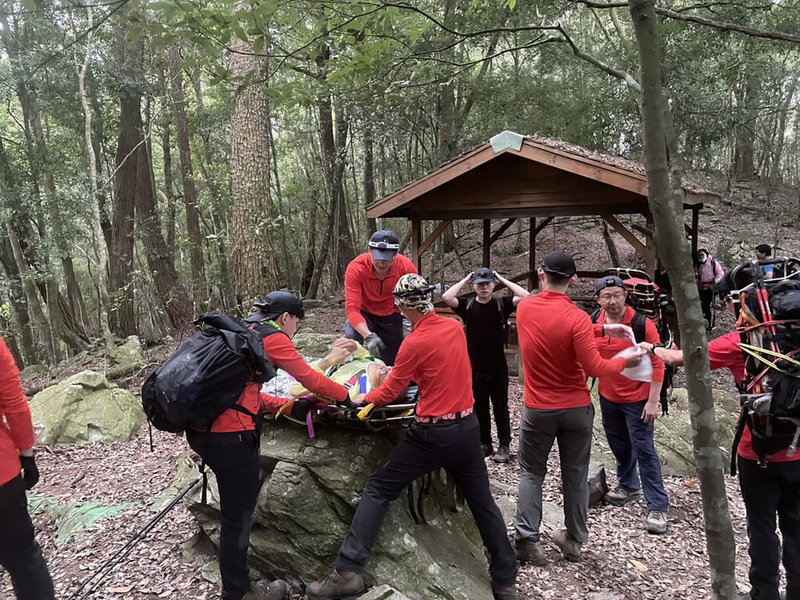 台中市消防局1日表示，30日上午11時47分接獲通報，一行9人的登山團攀登波津加山，70歲男性登山客摔落石縫，被救起時雙腳無法行走，搜救人員將受傷老翁放在籃式擔架搬運下山。（民眾提供）中央社記者趙麗妍傳真 112年5月1日