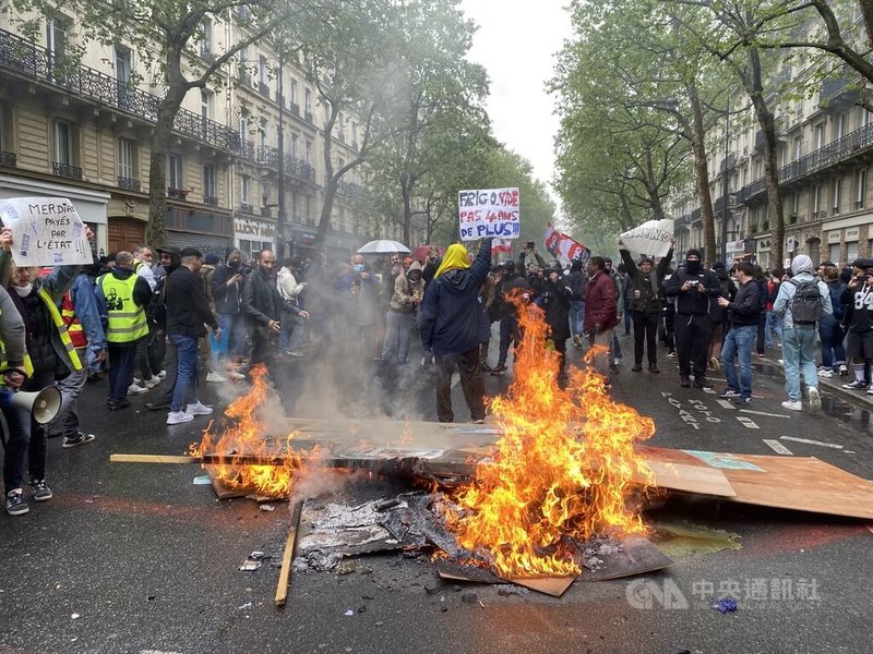 五一國際勞動節，法國各大城市有近80萬人走上街頭，抗議兩週前頒布的退制改革法。部分示威者焚燒物品，讓消防員疲於奔命，一名抗議男子在木板燃燒的大火前舉著「冰箱已空」標語。中央社記者曾婷瑄巴黎攝 112年5月2日