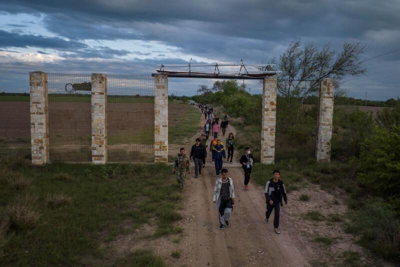 圖為中國移民從墨西哥渡河到德州邊界後，在德州國民警衛隊護送下到指定集合點。（路透社）