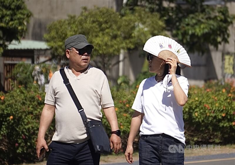 根據中央氣象局觀測，台南北寮6日下午1時40分出現攝氏40.1度高溫，是今年台灣氣溫首次突破40度。圖為高雄市鼓山區天氣炎熱，有民眾外出拿扇子遮陽。（中央社檔案照片）