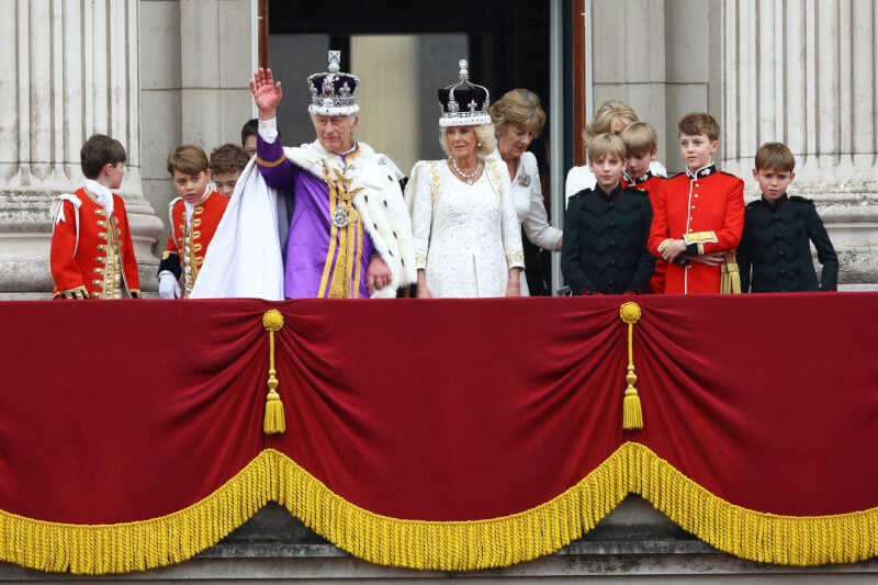 英王查爾斯三世（中左，揮手者）結束加冕典禮後，和王后卡蜜拉（中右）站在白金漢宮陽台，向民眾揮手致意。（路透社）