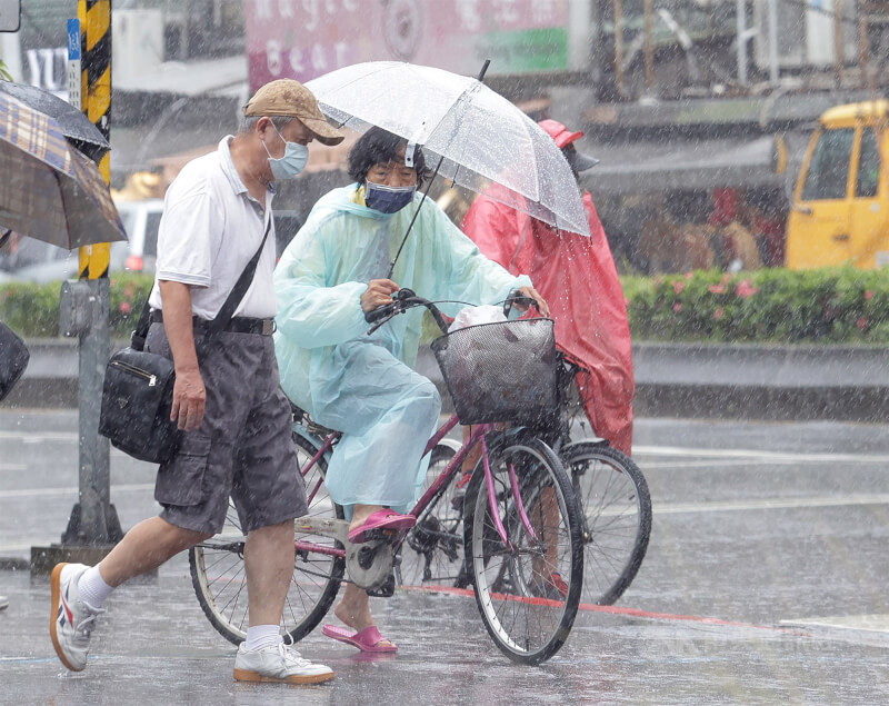 圖為台北市信義區民眾穿雨衣撐傘遮擋雨勢。（中央社檔案照片）