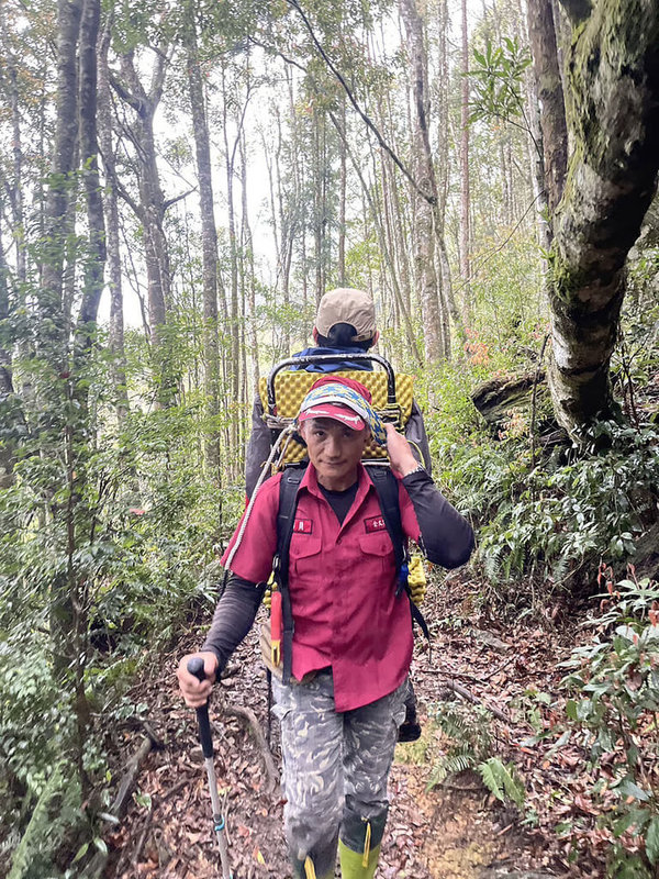 唐姓男子6日隨隊攀登南投縣信義鄉西巒大山，7日下山時疑高山症發作且膝蓋受傷，消防局人員獲報入山協助以人力背負唐男下山送醫。（南投縣消防局提供）中央社記者蕭博陽南投縣傳真  112年5月7日