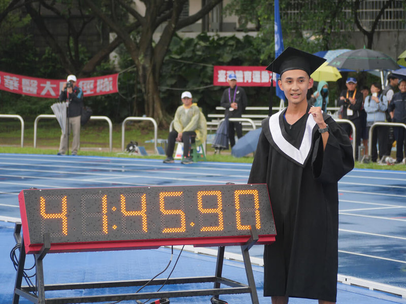 國立臺灣體育運動大學好手許嘉維8日在全大運男子1萬公尺競走繳出41分45秒90，打破全國紀錄，賽後換上準備好的學士服與計時器拍照。（全大運提供）中央社記者黃巧雯傳真  112年5月8日