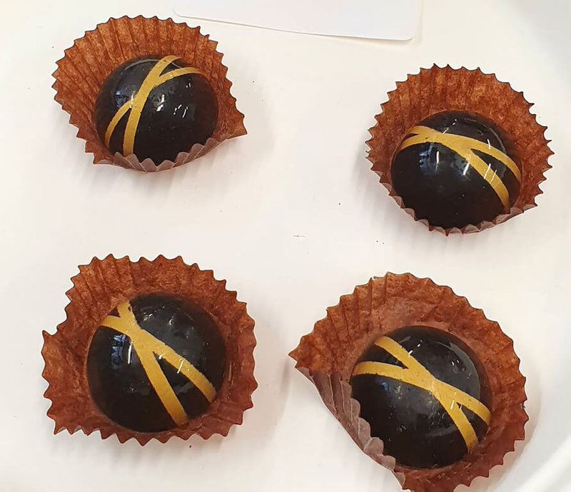 「英國巧克力學院」10日發布2022年「黃金巧克力糖」（Golden Bonbon）殊榮名單，獲獎品項都是評審團一致認定在年度競賽中值得特別肯定的珍品，其中包括長榮桂冠酒店的水蜜桃烏龍茶巧克力。（評審團成員林韋君提供）中央社記者陳韻聿倫敦傳真 112年5月11日