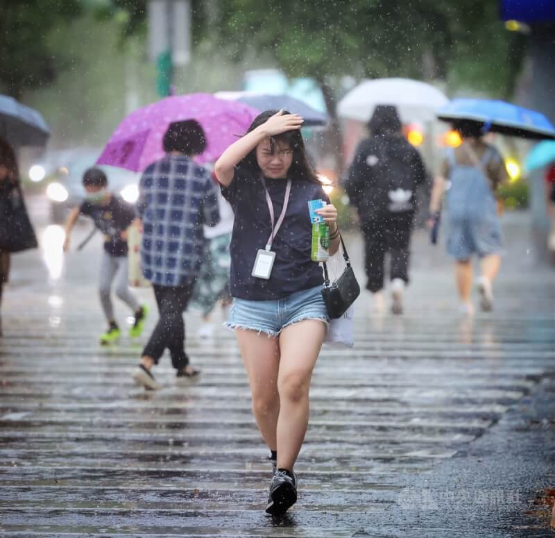 中央氣象局說，13日晚上起受到鋒面影響水氣增多，中南部雨勢明顯。圖為台北信義區民眾用手擋雨過馬路。（中央社檔案照片）
