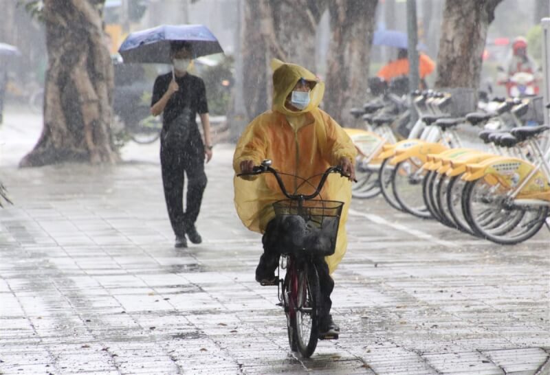根據氣象局資料，西南季風已進入南海，預估5月20日至6月初會逐漸向北推進，但台灣顯著降雨時間仍待觀察。圖為高雄市苓雅區民眾撐傘、穿雨衣遮擋雨勢。（中央社檔案照片）