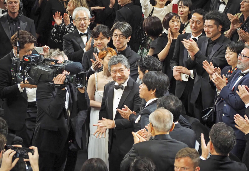 日本名導是枝裕和（中）與王牌編劇坂元裕二、已故音樂大師坂本龍一共同打造的電影「怪物」，17日晚間在坎城影展首映，放映後觀眾起立鼓掌長達9分半。（共同社）