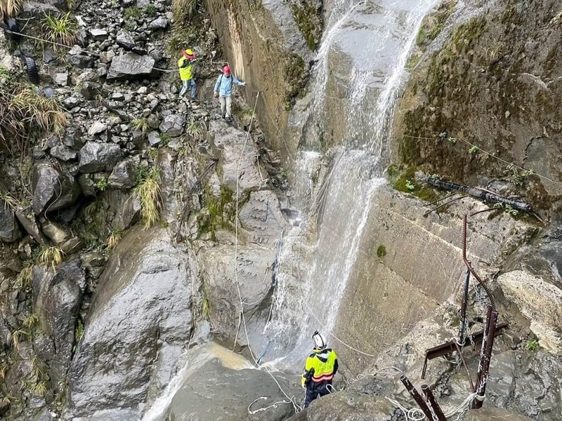 阿里山林鐵眠月線一處隧道崩塌處因19日下午降雨形成水瀑，20多名登山客受困，救援人員趕抵現場，待雨勢停，水瀑減緩，引導登山客陸續通過崩塌處，全部安全撤離。（嘉義縣消防局提供）中央社記者黃國芳傳真  112年5月20日