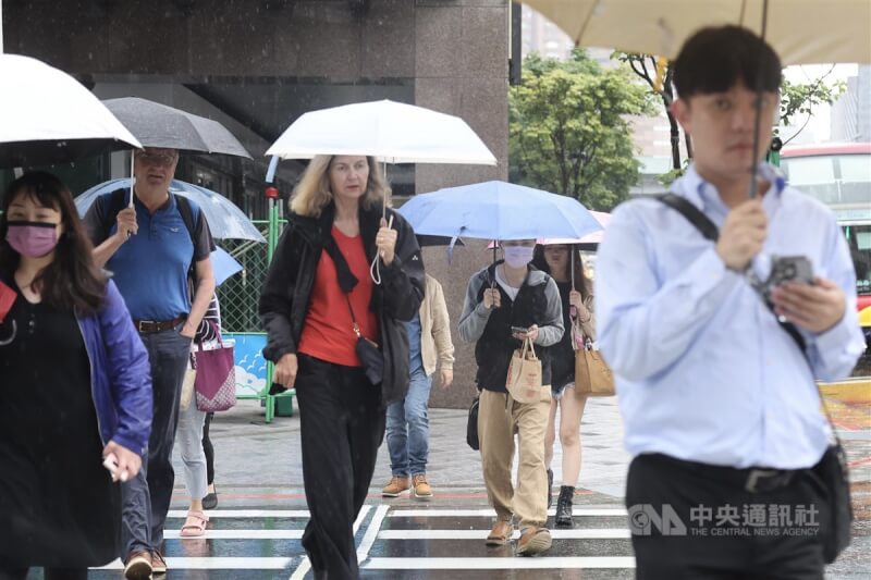 中央氣象局20日下午持續發布大雨及豪雨特報，包含新北市等11縣市要留意大雨或豪雨。圖為台北市中正區，民眾撐傘快步過馬路。中央社記者趙世勳攝 112年5月19日