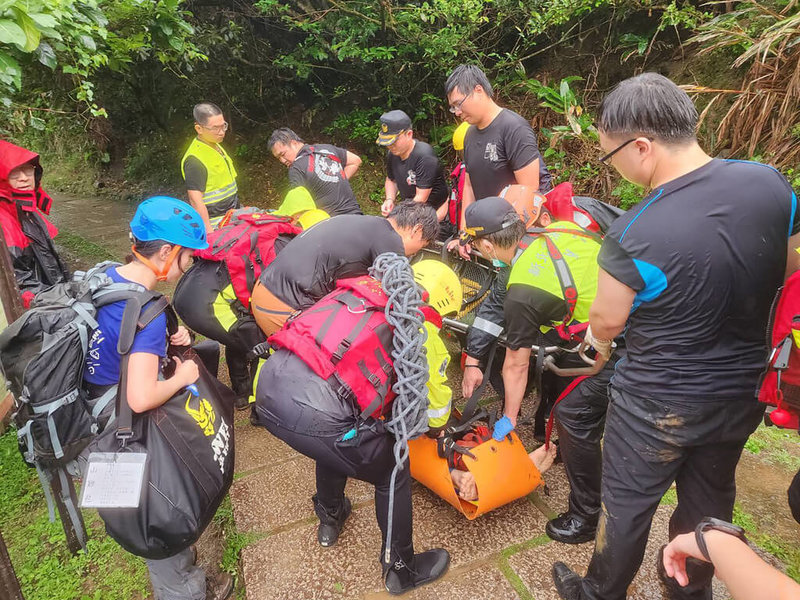 楊姓男子21日赴新北市貢寮區龍洞攀岩場攀岩時，不慎墜落距攀岩點約3公尺的地面受傷，搜救人員獲報到場，以長背板搭配軟式擔架將楊男搬至路面，隨後送醫治療。（讀者提供）中央社記者王朝鈺傳真  112年5月21日