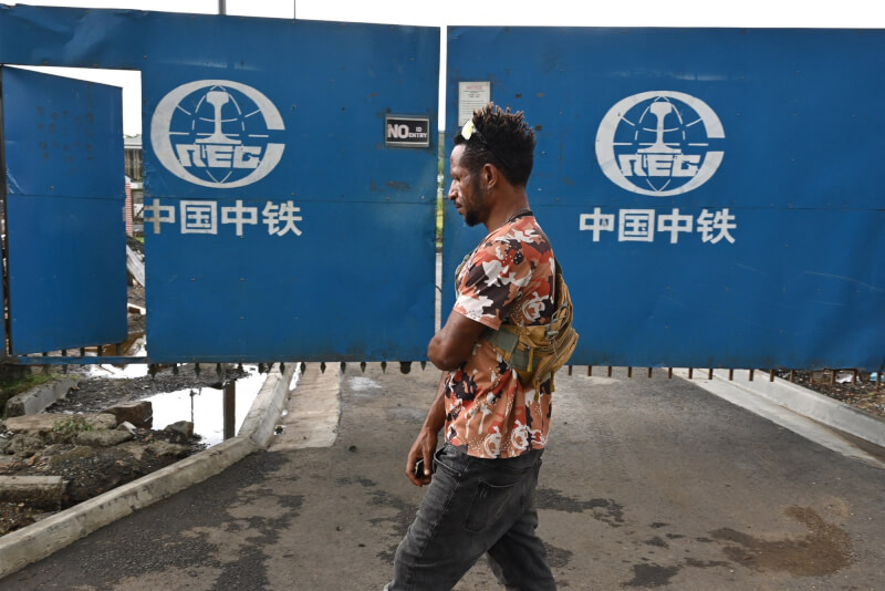 圖為一名男子18日經過中國中鐵公司在莫士比港建造的工地前。（法新社）
