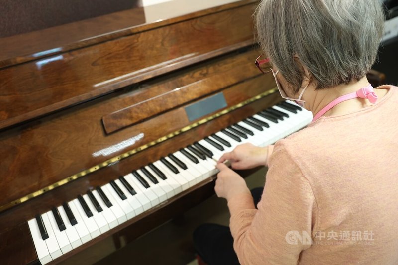 稻香日照中心的長者隨著音樂節奏以指尖彈奏鋼琴。中央社記者吳家昇攝 112年5月24日