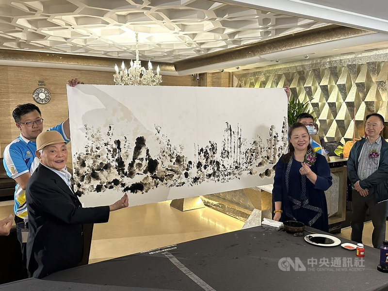 台中市豐原區五都大飯店舉辦「全國名人畫展」,邀請知名畫家柳清松(前左)為首名畫家,他25日現場示範以衛生紙代替畫筆,只見他手拿衛生紙沾取墨水,轉眼間已完成一幅山水名勝。中央社記者趙麗妍攝 112年5月25日