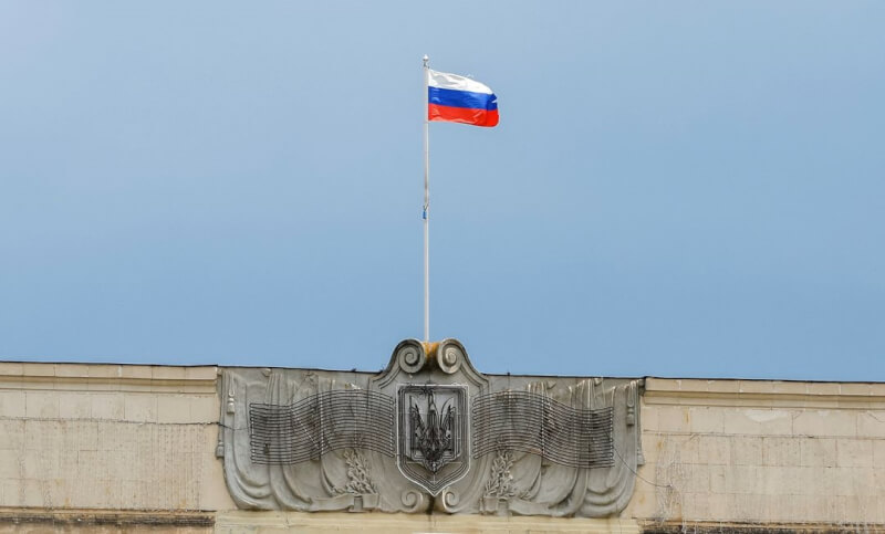 俄羅斯侵略烏克蘭後在占領區強推護照，有專家指出，這是為了證明俄羅斯占領的正當性，及抹除烏克蘭人的身分認同。圖為俄軍佔領的一個烏克蘭地方議會大樓，樓頂飄著俄羅斯國旗。（路透社）