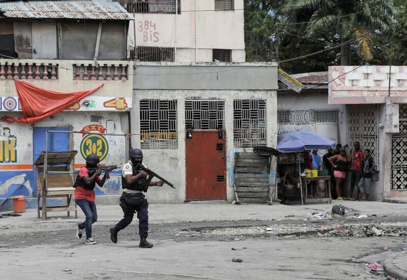 圖為4月25日，海地幫派分子襲擊警察局後，警察在街上巡邏，民眾擠在角落裡躲避。（路透社）