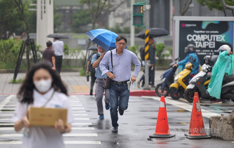 圖為台北市南港區民眾快速過馬路避雨。（中央社檔案照片）