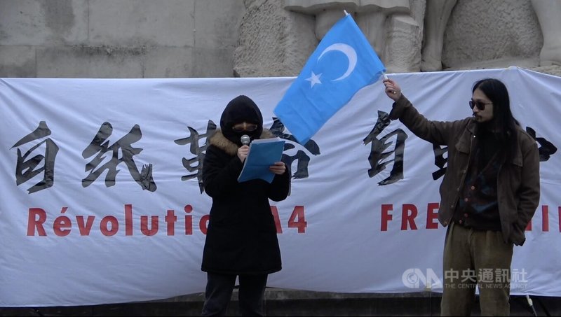 法國「反賊」社群的帶領者蔣不在2018年抵法後經常組織民主活動，社群從寥寥數人到如今約200人，經投票取名為「自由廣場」。圖為2022年12月3日「自由廣場」主辦的巴黎白紙革命運動，蔣不（右）為維吾爾族發言民眾高舉東突厥斯坦旗幟。中央社記者曾婷瑄巴黎攝 112年6月3日