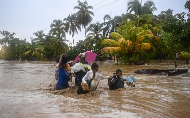 海地民防官員5日表示，週末降下暴雨引發洪災與山崩。圖為海地民眾3日走在被洪水淹沒的高速公路。（法新社）