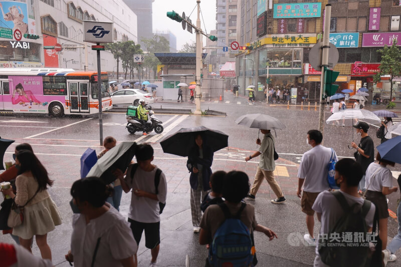 中央氣象局表示，11日起南海一帶的低壓北抬至台灣附近，各地會整天易有不定時的陣雨或雷雨。圖為台北捷運中山站外民眾撐傘擋雨，或在騎樓下避雨。（中央社檔案照片）