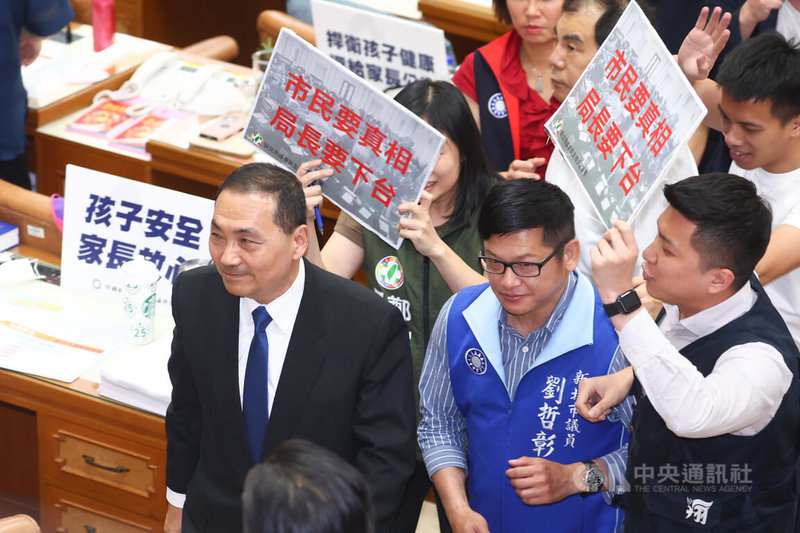 新北某幼兒園疑餵藥案引發各界關注，新北市長侯友宜（前左）13日列席新北市議會說明並回應議員質詢，離去時遭民進黨籍新北市議員上前舉牌抗議。中央社記者王騰毅攝 112年6月13日