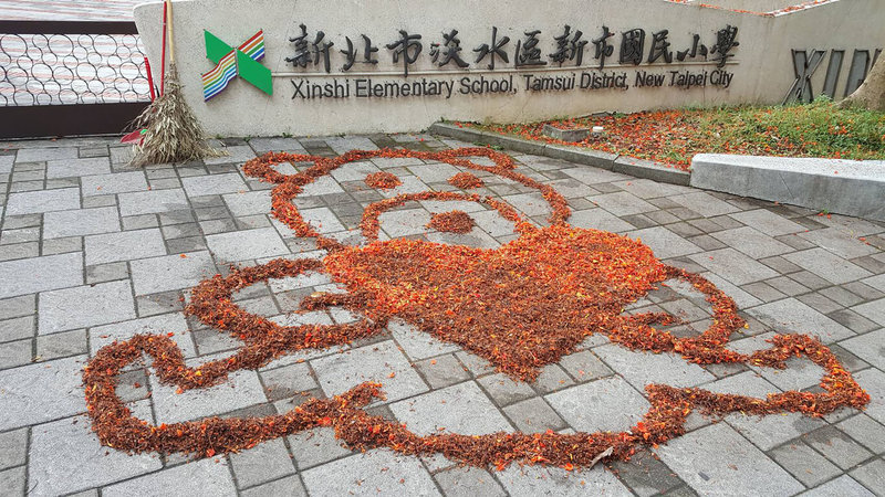 新北市淡水區新市國小程姓警衛連兩週掃鳳凰花瓣作畫,畫面被貼上網路獲熱烈迴響,有網友留言表示很感謝程姓警衛,「讓孩子每天對上學都有期待」。(新市國小提供)中央社記者高華謙傳真 112年6月14日