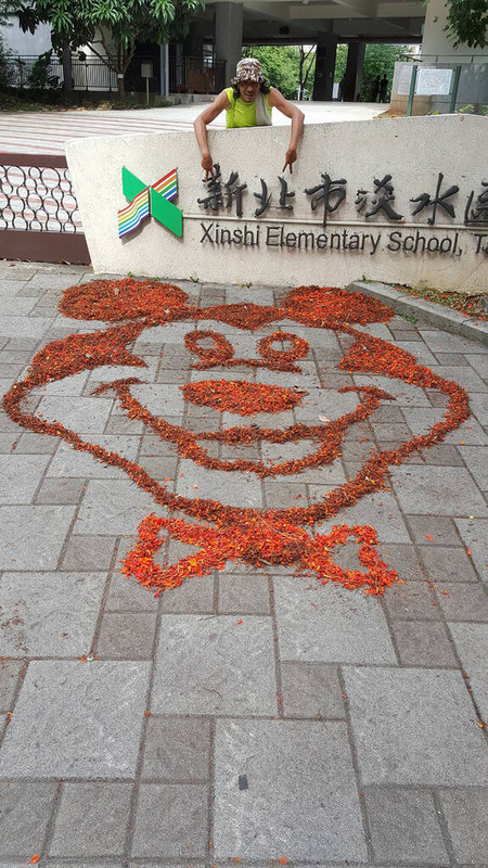 新北市淡水區新市國小程姓警衛擔任警衛已8年,與學生感情好,近期整理校園環境時利用鳳凰花瓣在地上作畫,讓孩子們又驚又喜。圖為程姓警衛所創作的米奇。(新市國小提供)中央社記者高華謙傳真 112年6月14日