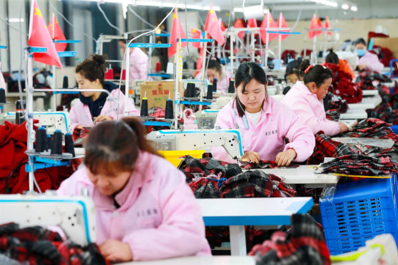 圖為3月安徽省淮北市婦女在工廠加工服裝。（中新社）