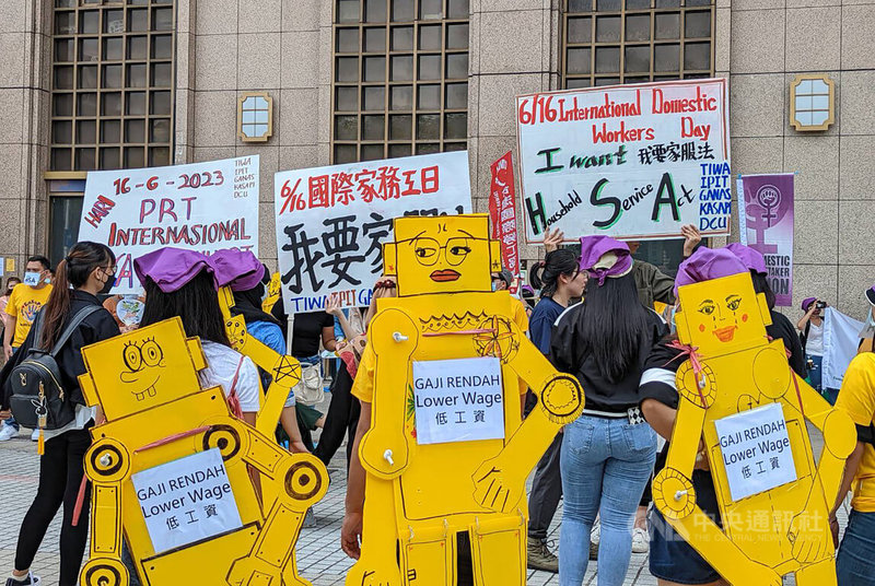 多個移工團體18日在台北車站發起快閃行動，與會者身揹黃色機器人造型看板，分別貼上「長工時、低工資、沒休假」等字句，繞行台北車站1圈表達訴求。中央社記者張雄風攝  112年6月18日