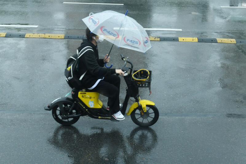 圖為17日安徽省阜陽市，民眾在雨中撐傘騎車。（中新社）