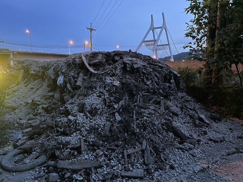 苗栗縣銅鑼鄉客屬大橋下空地屢遭傾倒廢棄物，鄉民代表徐裕逢表示，21日傍晚民眾發現橋下又被亂倒，橋下瑞興街出現大量疑似工地廢棄物，宛如一座小山，還占據車道連機車都無法通行。（徐裕逢提供）中央社記者管瑞平傳真  112年6月21日