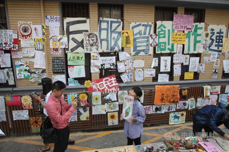 圖為2014年4月反服貿學運退出立法院議場前夕，民眾在立法院外牆和活動標語合影。（中央社檔案照片）