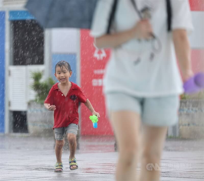 圖為10日北市大佳河濱公園兒童戲水區玩水的小朋友遇大雨，趕緊跟著媽媽一起避雨。（中央社檔案照片）