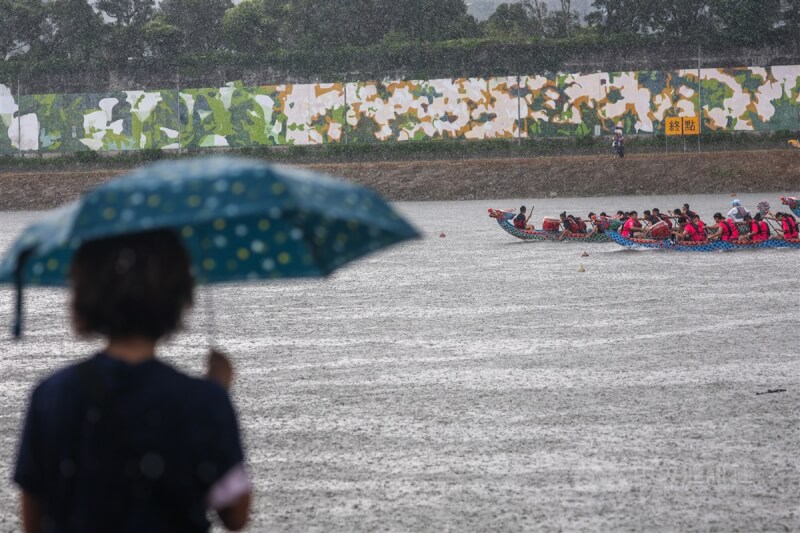 圖為23日台北國際龍舟錦標賽選手在雨中奮力划槳，岸邊民眾撐傘加油。（中央社檔案照片）