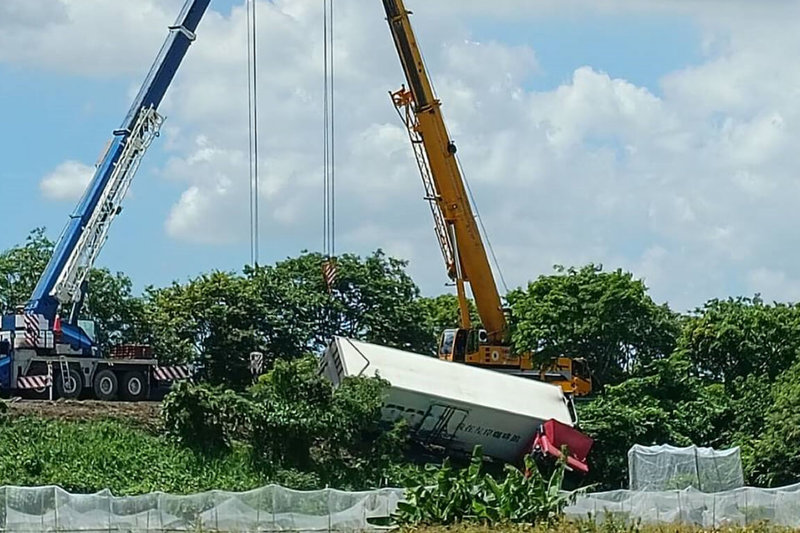 1輛聯結車2日上午行經國道1號南向台南下營附近路段疑因爆胎失控衝落邊坡，警方調派大型吊車進行吊掛作業。（讀者提供）中央社記者楊思瑞台南傳真  112年7月2日