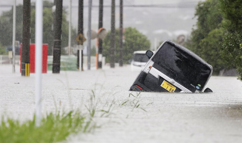 10日福岡街頭汪洋一片，汽車被困在淹水的道路上。（共同社）