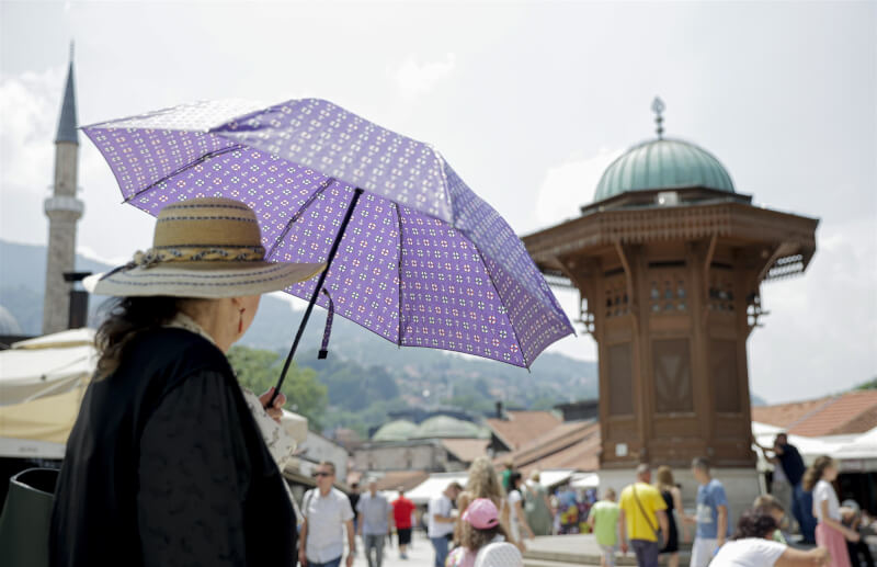 圖為歐洲波士尼亞一名婦人6日在市區撐傘遮陽。（安納杜魯新聞社）