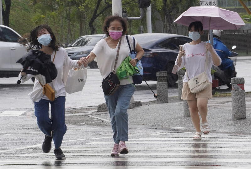 圖為高雄午後下起陣雨，街頭民眾快跑過馬路。（中央社檔案照片）