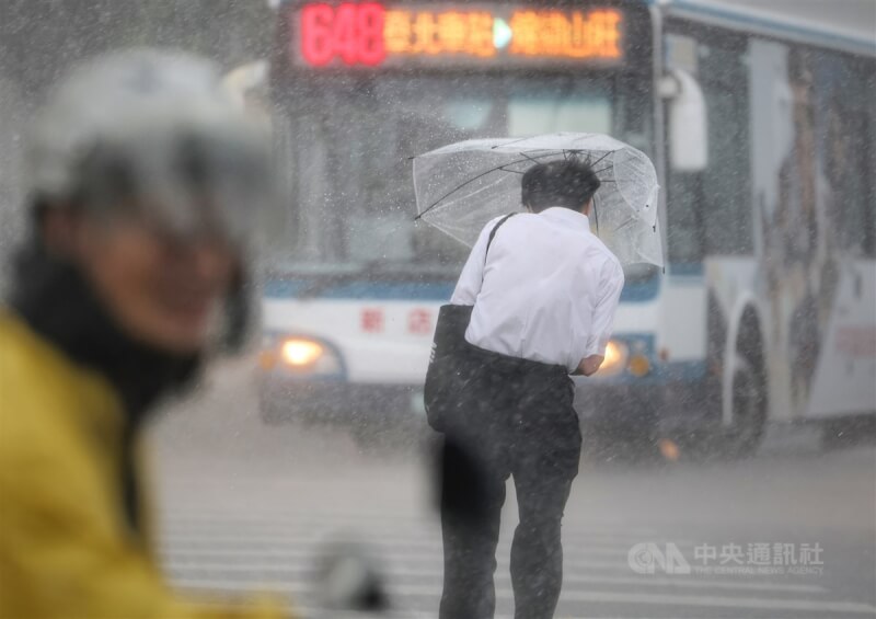 中央氣象局對19縣市發布大雨特報,對流雲系發展旺盛,易有短延時強降雨。圖為台北市中正區中午下起大雷雨,民眾撐傘遮擋強風及雨勢。(中央社檔案照片)