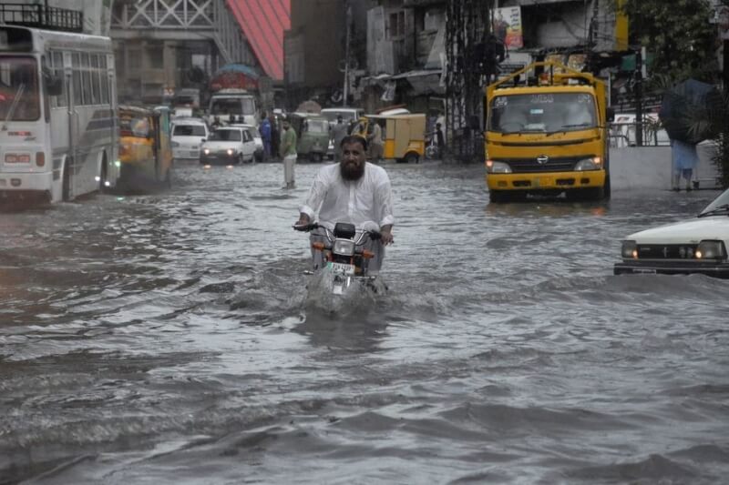 圖為19日印度拉瓦爾品第一名民眾在已淹水的街上騎車。（路透社）